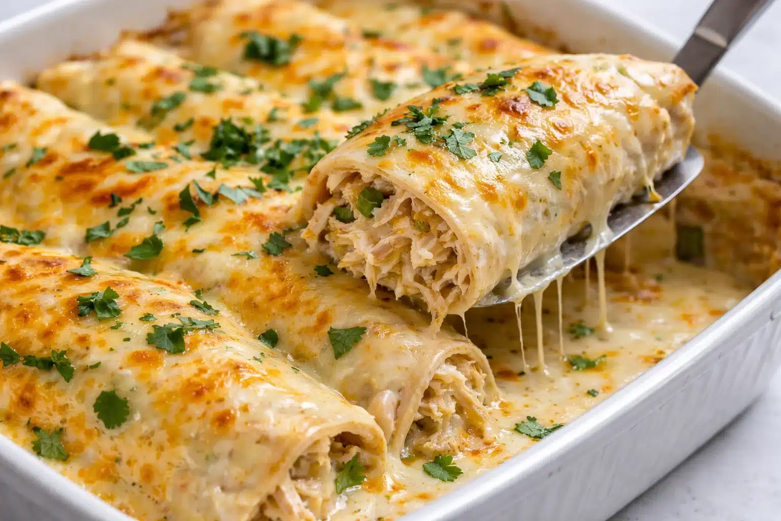 Creamy white chicken enchiladas topped with cheese and sour cream